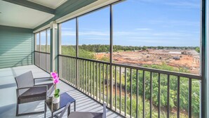 A balcony with a view of a construction site, a table with a vase of flowers, and two chairs. - Spacious Resort Suite w/ Pool & Sauna near Disney (Winter Garden)