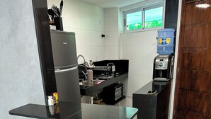 A modern kitchen with a refrigerator, coffee machine, and a water dispenser. There are two cork wine stoppers in front of the counter.