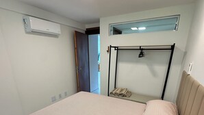 A bedroom with a bed, an air conditioning unit, a window, and a ceiling light.