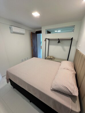 Ein Schlafzimmer mit einem Bett, einer Klimaanlage, einem Fenster und einer Deckenleuchte.