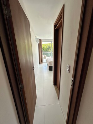 Ein Hotelkorridor mit Blick auf einen Balkon, ein Bett und einen Stuhl.