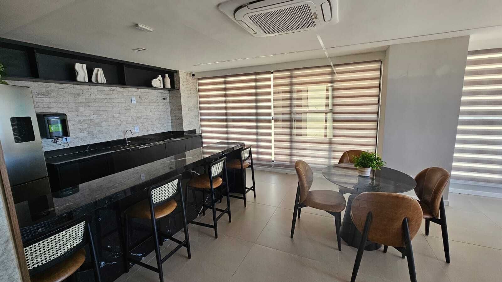 A modern kitchen with a bar area, dining chairs, and a table with a potted plant.