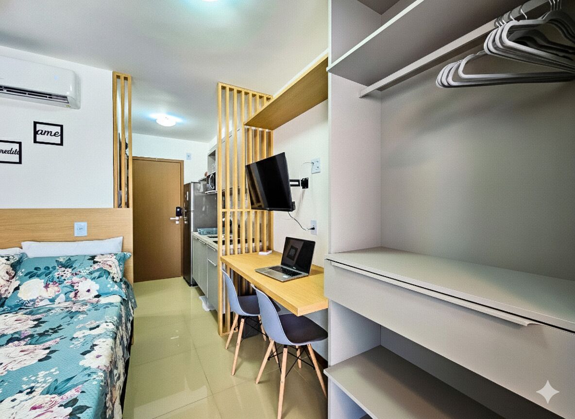 Una camera d'albergo con un letto, una scrivania con un portatile, una televisione e un armadio.