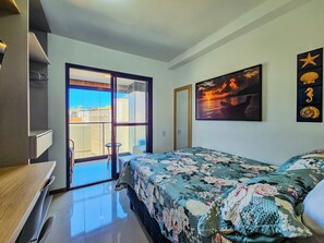 Quarto com cama, escrivaninha, cadeira, janela com vista e um quadro pendurado na parede.