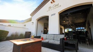 An outdoor seating area with a wooden table, a sofa, and a bar/lounge entrance. - Resort Home, Private Pool and Spa, Outdoor Theater (Kissimmee)