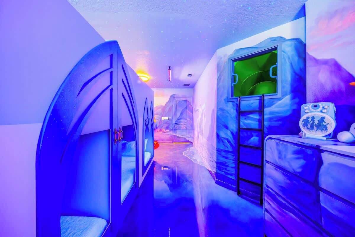 A room with a bunk bed, a ladder, a window, and a wall with a mountain design.