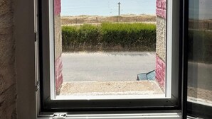 Una ventana con vista a una playa, una valla y una carretera.