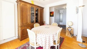 A dining area with a round table, chairs, a wooden cabinet, and a globe on a stand. - Le sable au pied de la résidence T2 de qualité (Larmor-Plage)