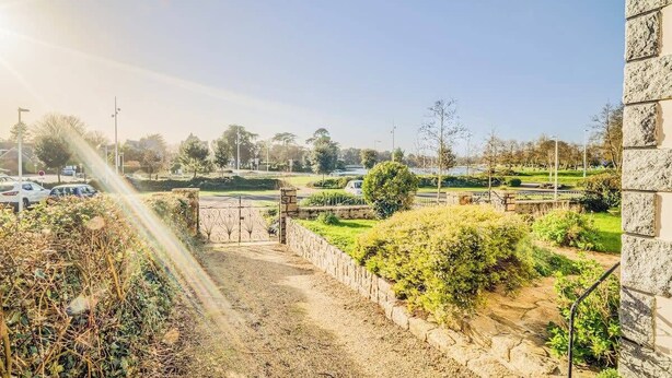 A paved pathway leading to a gated entrance, surrounded by greenery and a stone wall. - Spacieuse résidence de famille cadre privilégié (Loctudy)