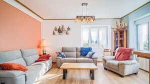 A living room with a sofa, armchair, coffee table, and a ship model on a cabinet. - Spacieuse résidence de famille cadre privilégié (Loctudy)