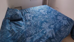 Een slaapkamer met een bed, een raam en een muur met drie schilderijen.