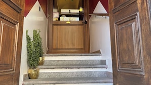 Una puerta de madera con 'HR', que da a una habitación con pared blanca y detalle rojo.