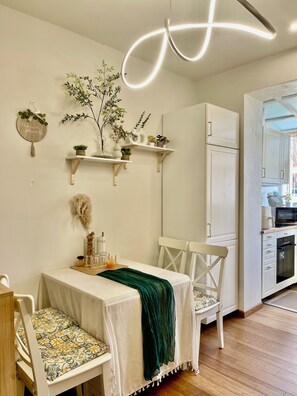 A modern kitchen with white cabinets, a dining table with chairs, and a hanging light fixture. - Happy Nest Tuscany Between Florence and Rome (Castiglion Fiorentino)