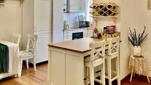 Une cuisine moderne avec des meubles blancs, un îlot central en bois et un coin repas avec des chaises blanches.