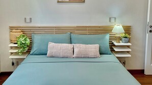 Un lit bien fait, avec une couverture verte, deux oreillers et des serviettes pliées.