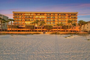 Ein mehrstöckiges Hotel mit Balkonen in der Nähe eines Sandstrandes.