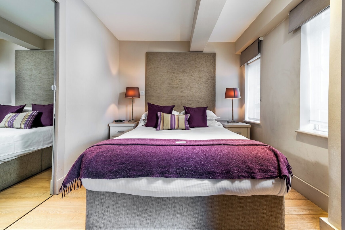 A modern bedroom with a large bed, two bedside tables, a headboard, and a window.
