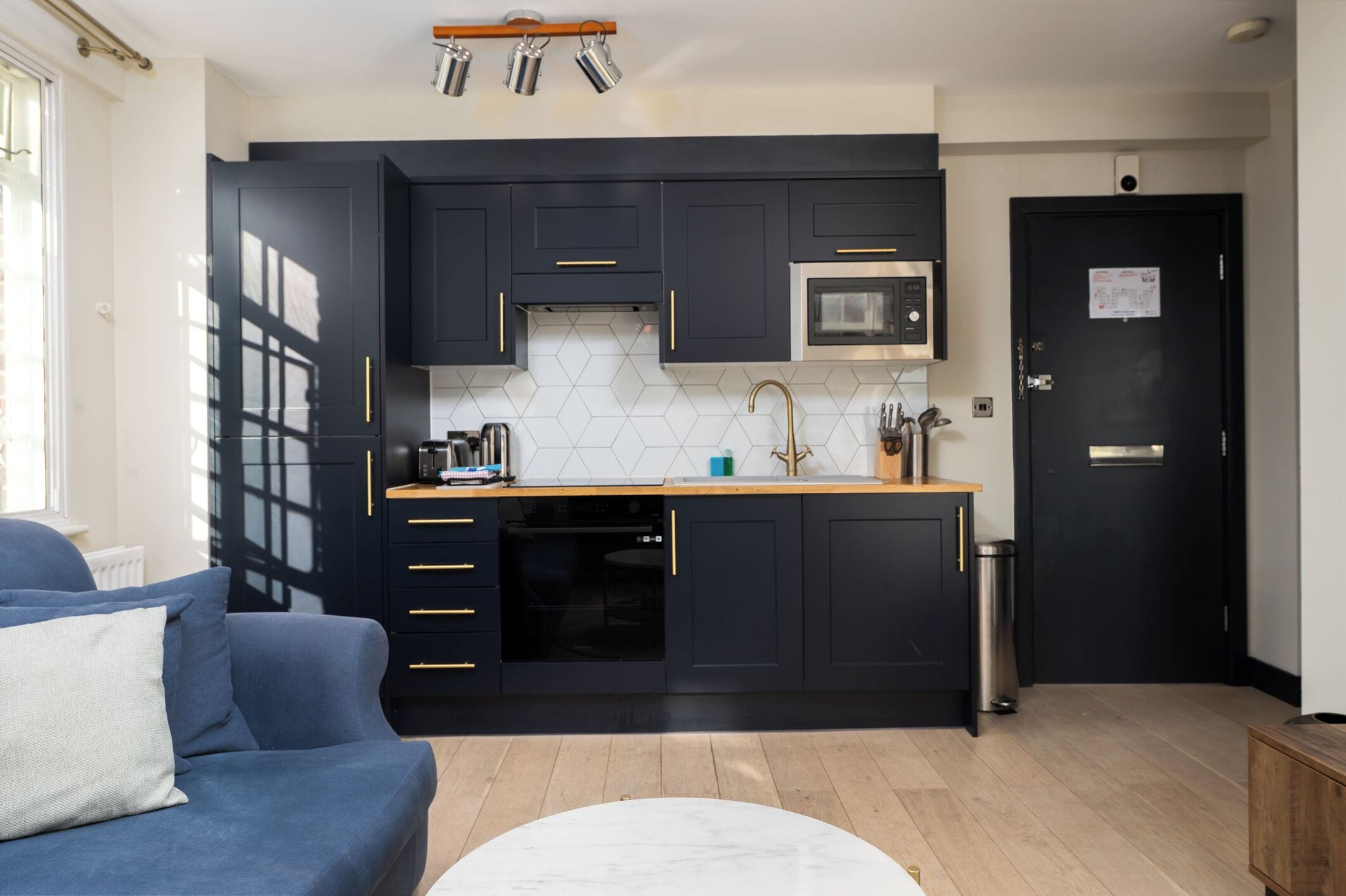 A compact kitchen with dark cabinets, a microwave, and a sink.