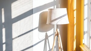 A room with a tripod lamp, a wooden bowl, and a table by a window with curtains. - Nell Gwynn House Apartments & Rooms (London)