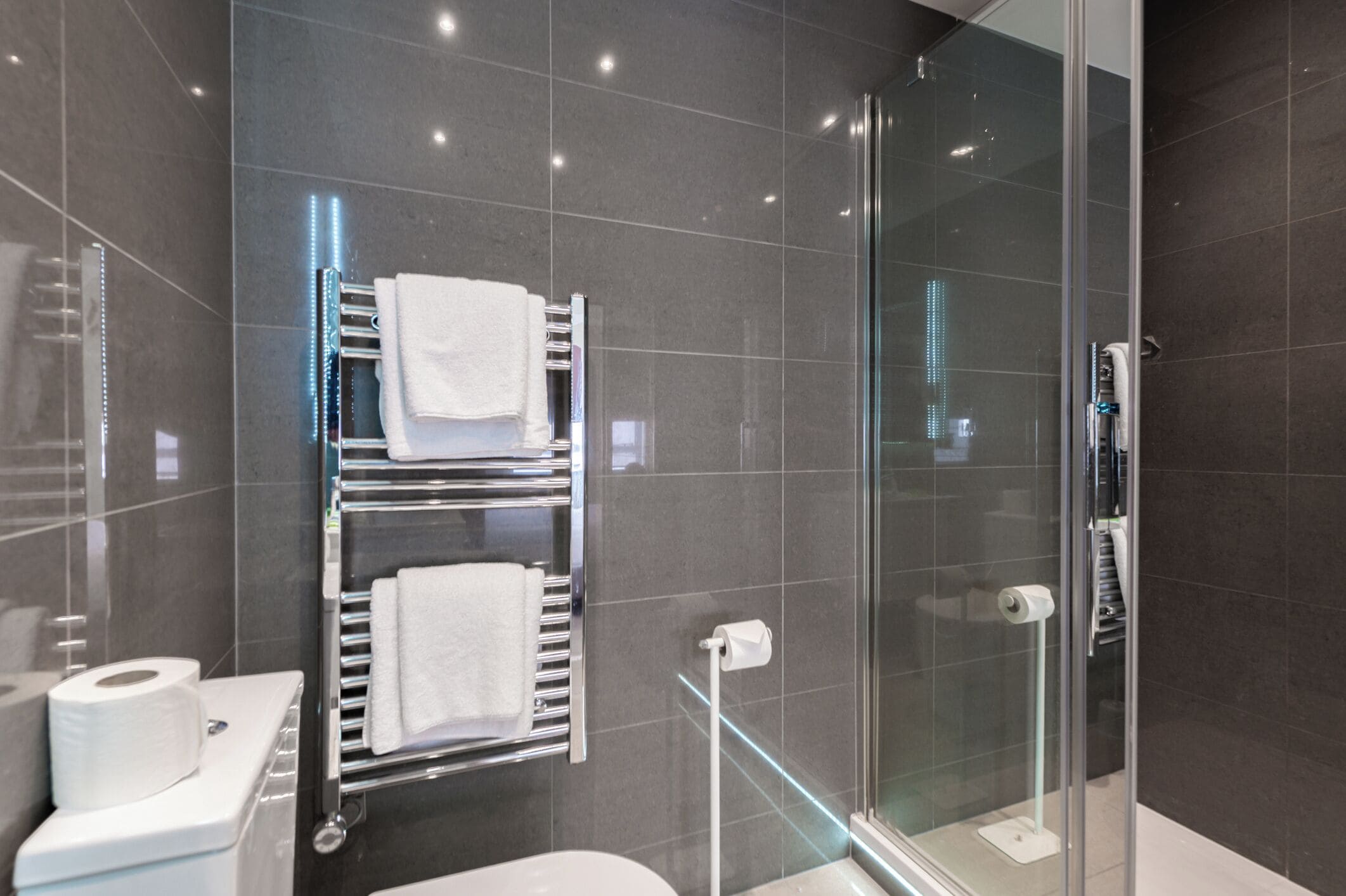 Un bagno moderno con box doccia in vetro, portasci e WC.
