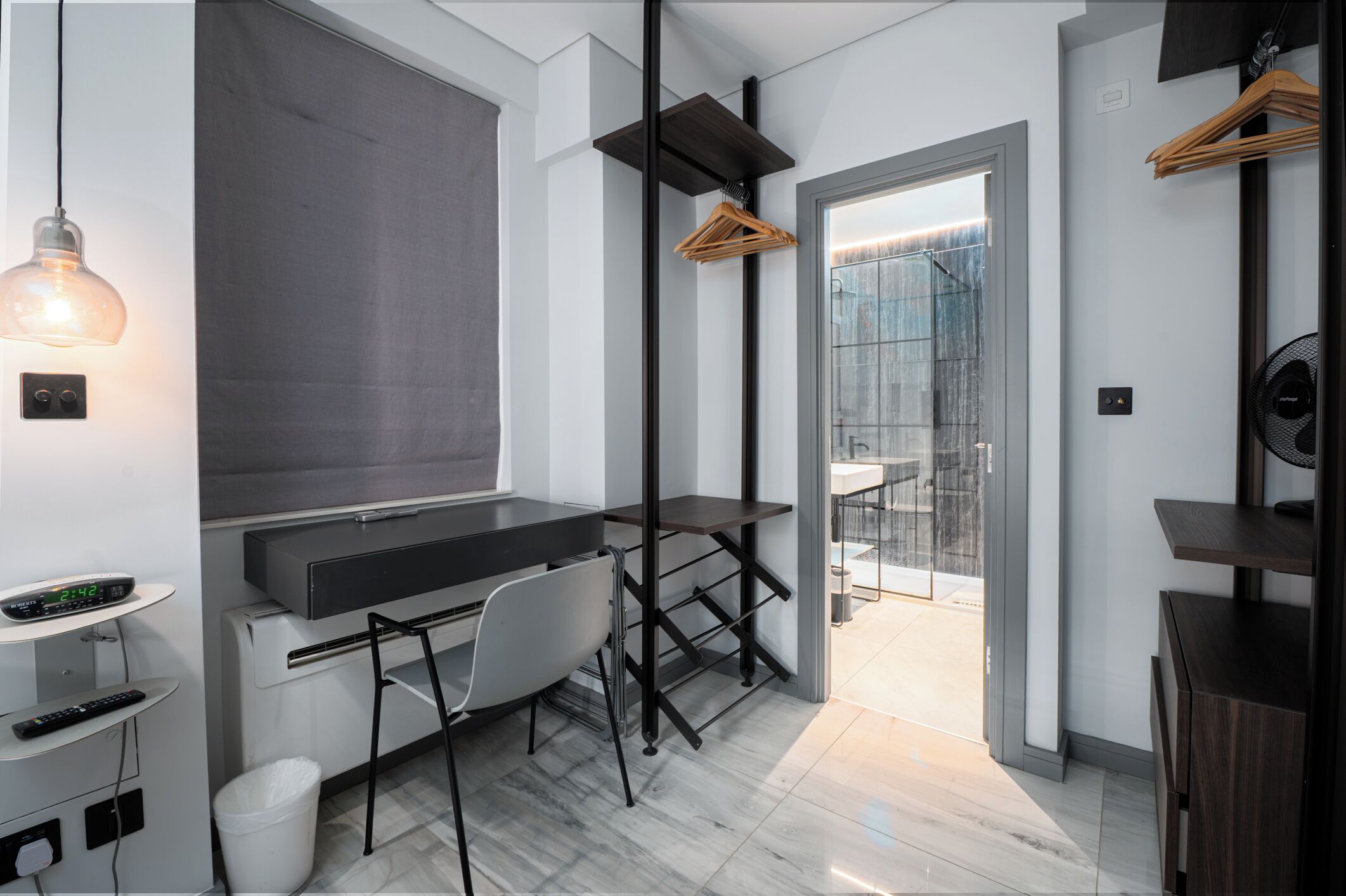 A modern room with a desk, chair, and a hanging light fixture.