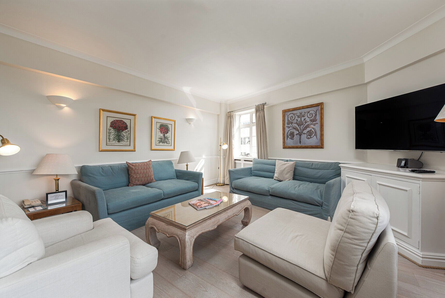 A living room with two sofas, a coffee table, a TV, and framed artwork on the walls.
