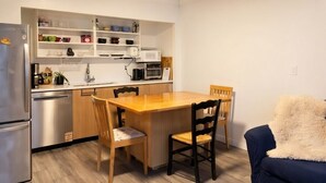 A compact kitchen with a wooden table and chairs, a microwave, and a refrigerator.