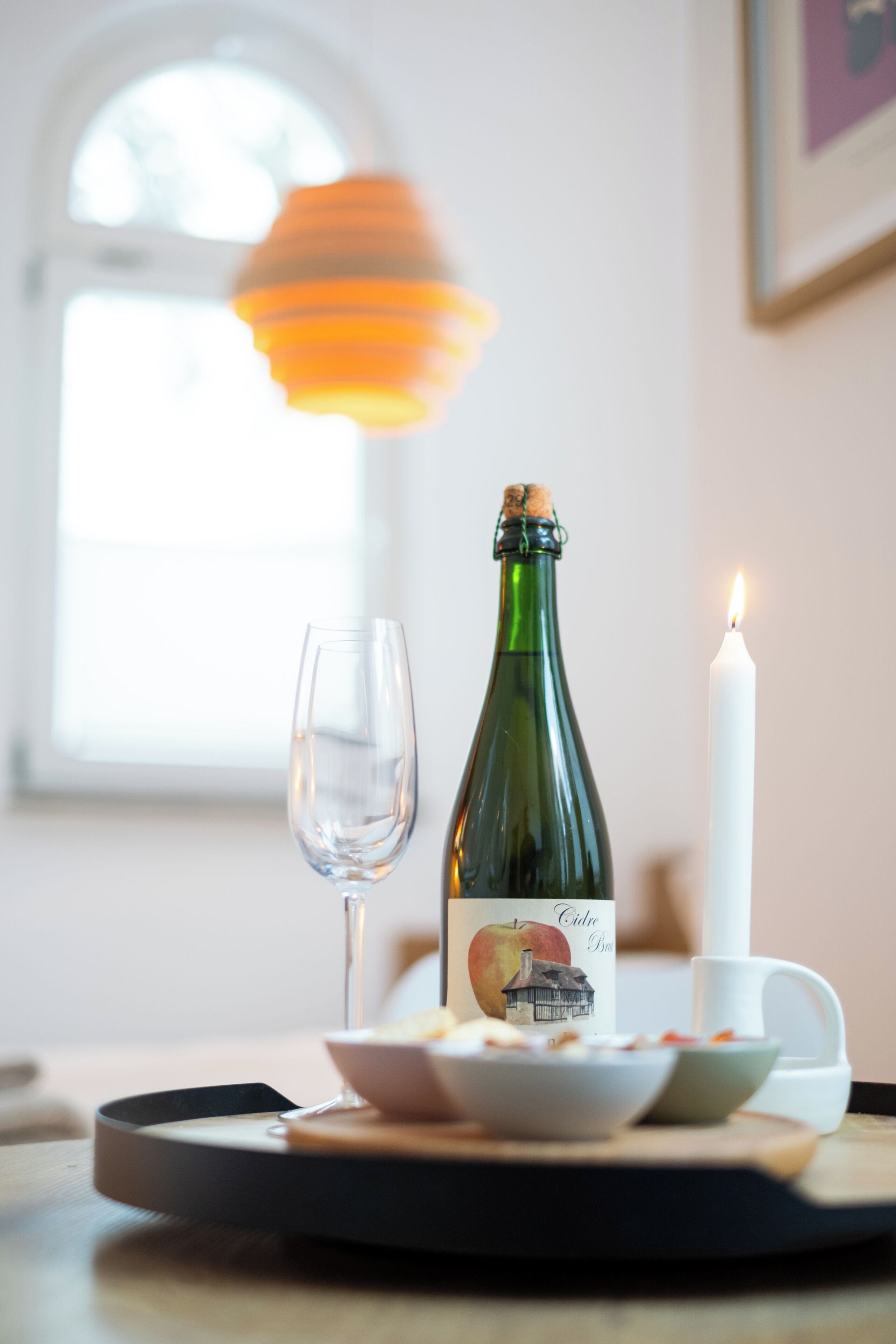 Una mesa con una botella, una vela y un vaso.