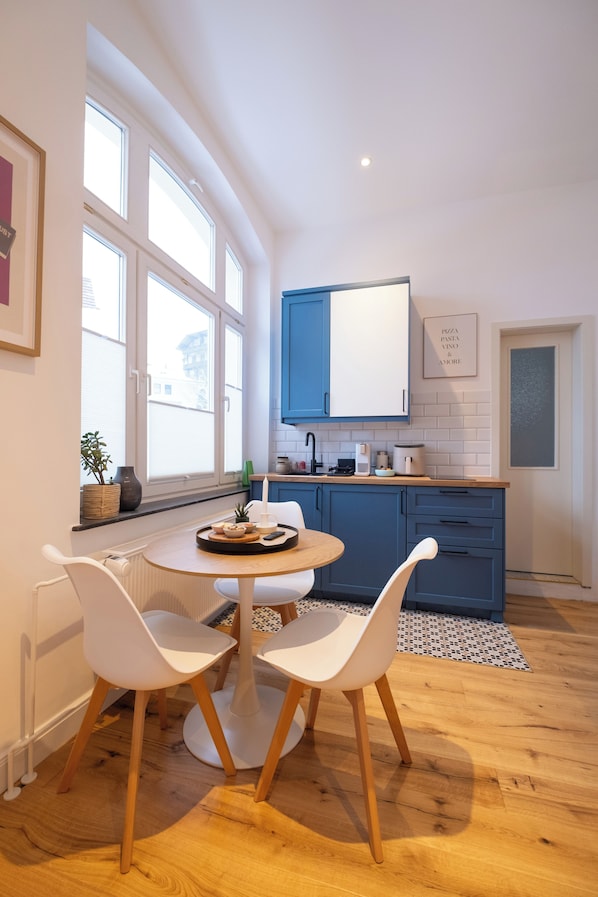 Une cuisine moderne avec des meubles bleus, une table ronde en bois et des chaises blanches.
