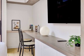A modern kitchen with a wooden countertop, a TV mounted on the wall, a framed picture, a potted plant, and a chair. - w* | Soft Light Loft in the Heart of Bogotá (Bogotá)