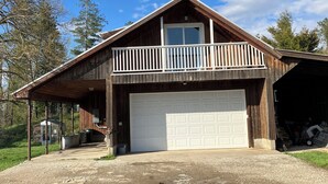 Ein zweistöckiges Holzhaus mit Garage, Balkon und überdachter Veranda.