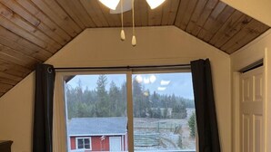 Ein Schlafzimmer mit Holzboden, einem Bett, einer Schiebetür zu einem Balkon und einem Deckenventilator.