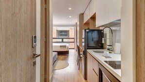 A modern kitchen with a refrigerator, sink, and wooden cabinets.