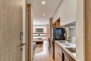 A modern kitchen with a refrigerator, sink, and wooden cabinets. - w* | Signature Loft in the Heart of Bogotá (Bogotá)