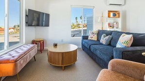 A modern living room with a sofa, round coffee table, and a flat-screen TV mounted on the wall. - 10 Mins To Joshua Tree National Park & Marine Base. Fire Pit, Romantic Retreat (Twentynine Palms)