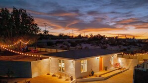 A modern house with a flat roof, a covered patio, and a well-lit entrance. - 10 Mins To Joshua Tree National Park & Marine Base. Fire Pit, Romantic Retreat (Twentynine Palms)