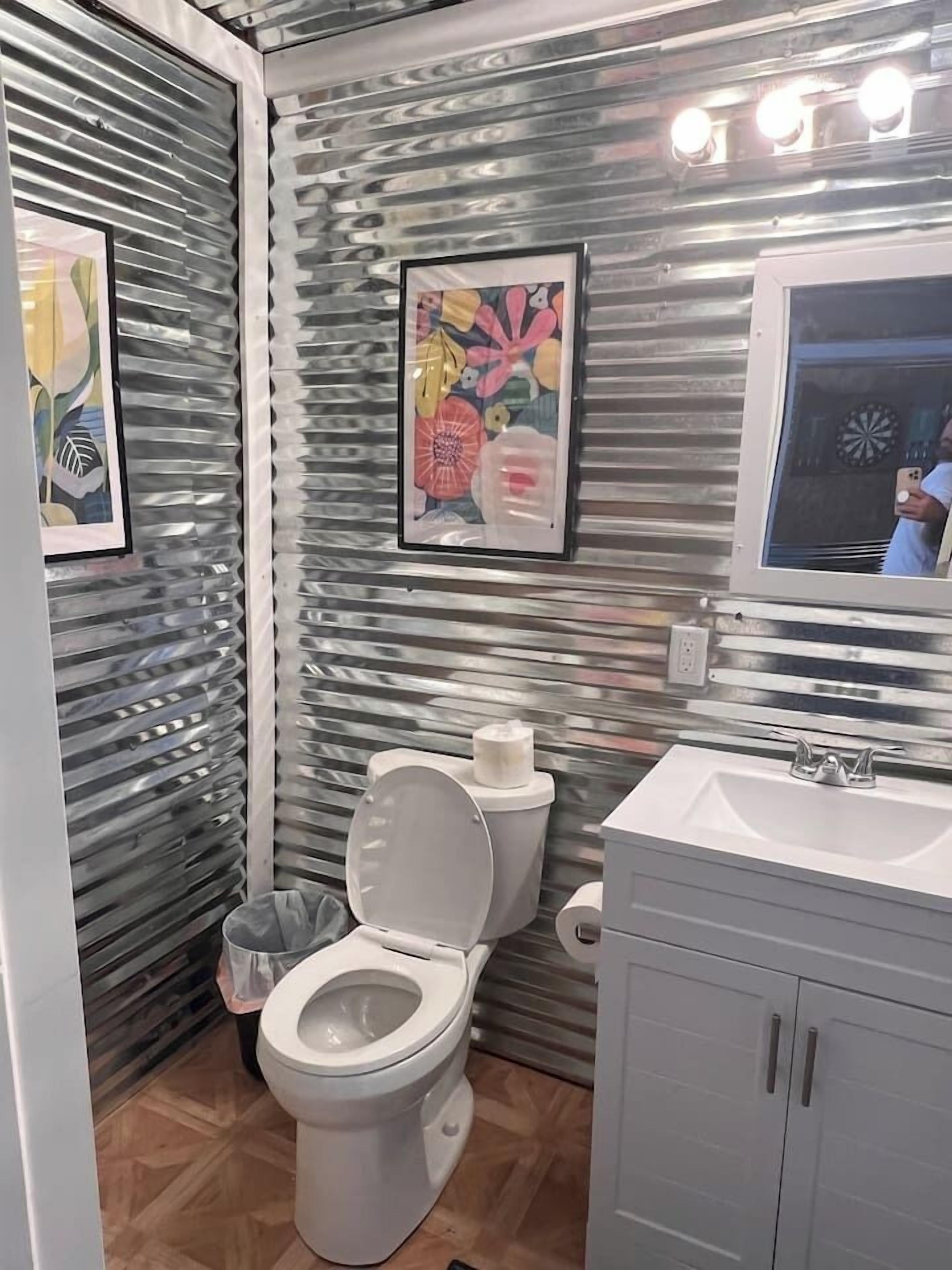 A bathroom with a toilet, sink, and framed artwork on the wall.