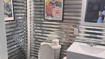 A bathroom with a toilet, sink, and framed artwork on the wall.