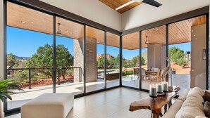 A spacious room with large windows, a wooden ceiling, and a view of the outdoors. - Luxury NEW home Built 2024-Pool-Sedona Red Rock Views (Sedona)