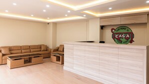 Ein moderner Empfangsbereich mit einer Couch, einem Couchtisch und einer Rezeption.