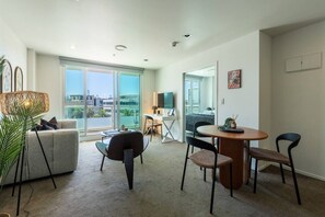 A modern apartment with a large balcony, a dining area, and a living room with a sofa and chairs. - Bright & Cosy CBD Retreat Near Britomart (Auckland City)