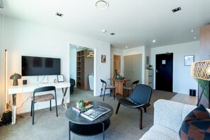 A modern living room with a flat-screen TV, a dining table, and a sofa. - Bright & Cosy CBD Retreat Near Britomart (Auckland City)