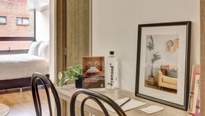 A hotel room with a bed, a framed picture, a bottle, and a brochure on a table. - w* | Fabulous Loft in Bogota w/ Gym (Bogotá)