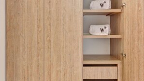 Un armadio in legno con tre ripiani, ognuno dei quali contiene un asciugamano bianco con un simbolo 'W' nero.