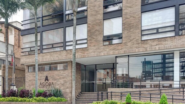 Un edificio moderno con facciata in mattoni, ampie finestre e un cartello con la scritta 'AGORA'.
