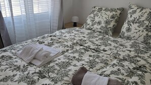 Ein Bett mit Blumenmuster auf der Bettwäsche, zwei Handtücher und eine Nachttischlampe.