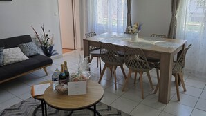 A dining area with a wooden table, chairs, a clock, and a window with curtains. - Sejour eau vive, 3 bedrooms Near metro and créteil village (Créteil)