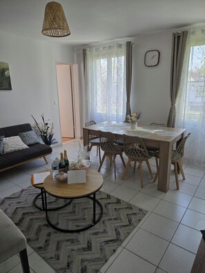 A dining area with a wooden table, chairs, a clock, and a window with curtains. - Sejour eau vive, 3 bedrooms Near metro and créteil village (Créteil)