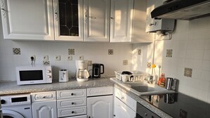 Eine Küche mit weißen Schränken, einer Mikrowelle, einer Kaffeemaschine, einem Toaster, einer Spüle und einem Geschirrspüler.
