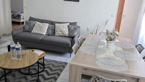 Ein Wohnzimmer mit einer Couch, einem Esstisch mit Stühlen, einem Couchtisch und zwei Bildern an der Wand.